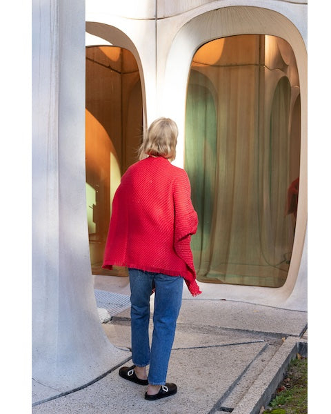 Back view of woman wearing Wehve Ava:AN cape in concrete setting