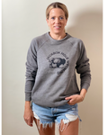 A person wearing a gray sweatshirt with 'Jackson Hole' and a bison graphic on it, standing against a neutral background.