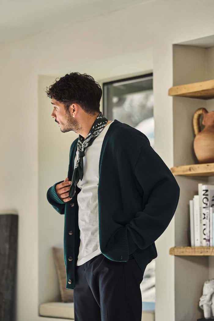 Male model wearing green v neck cardigan in Scarab green indoors