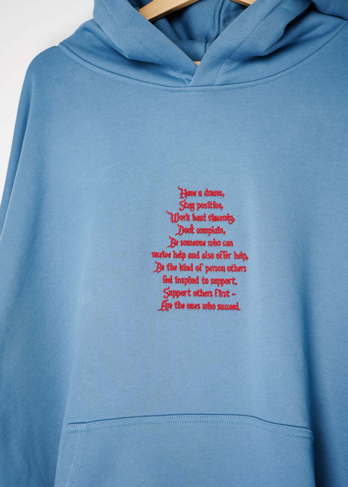 Close-up of the embroidered message on a lightweight terry hoodie, featuring positive affirmations in red on a blue background.