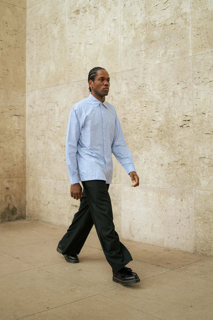 model wearing men's striped casual shirt styled with black trousers walking outdoors