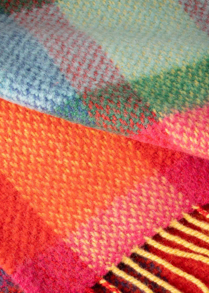 Close-up of a colorful plaid fabric with red, orange, green, and blue patterns.