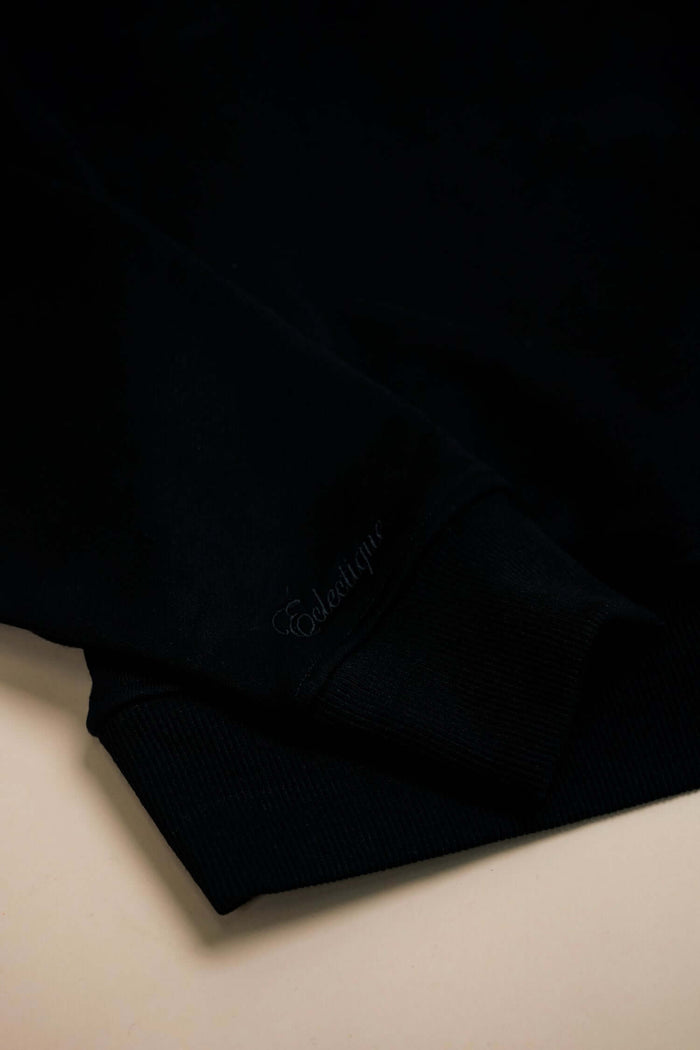 Detail of Midweight Cotton Hoodie with Script Logo | Éclectique showcasing the black fabric and logo.