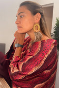 Aboriginal Woman wearing Aboriginal designed kimono and woven gold earrings with emu feathers