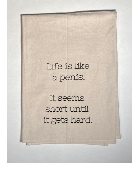 A beige cotton tea towel with black printed text that reads: 'Life is like a penis. It seems short until it gets hard.'